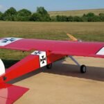 red and white plane on brown field during daytime