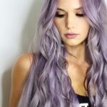 purple haired woman in black top leaning on wall